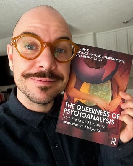 Tobias Wiggins holding book "The Queerness of Psychoanalysis: From Freud and Lacan to Laplanche and Beyond"