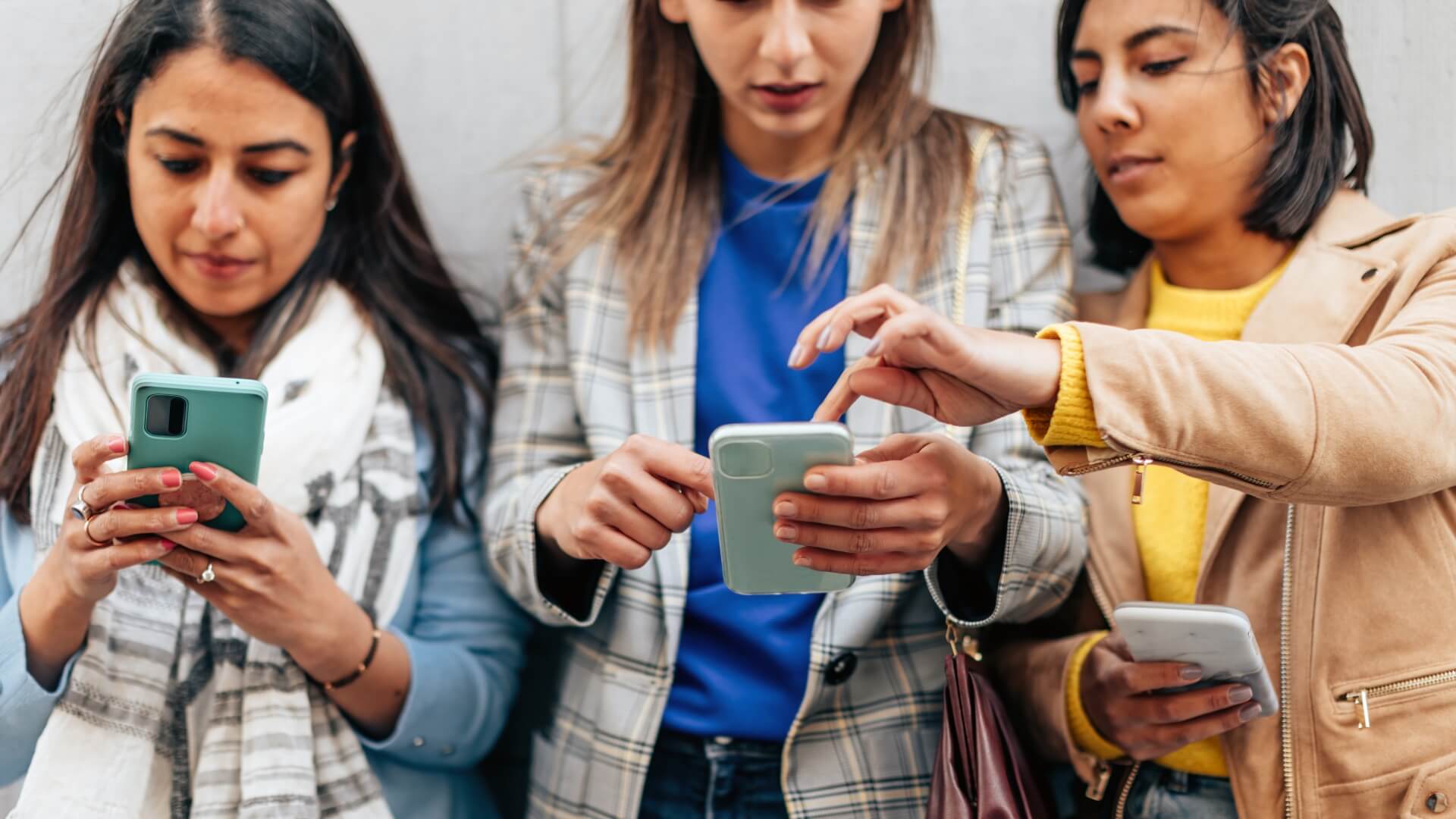 three multiethnic young women looking at cell phones